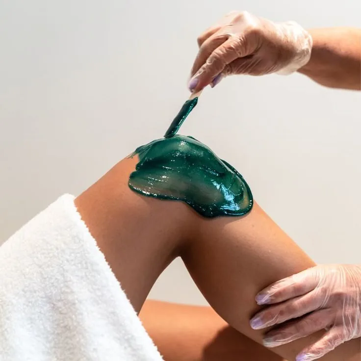 Hard wax being applied during a professional body waxing service